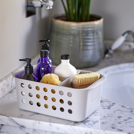 Opbergbox voor badkamer op een marmer wastafel gevuld met badkamerproducten