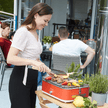 Rode BBQ e-carlo elektrische tafelgrill met vlees en groenten op de rooster met vrouw die met een tang vlees omdraait