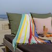 Hamamdoek multicolour met franjes aan de onderkant op strandbed me de zee als achtergrond  