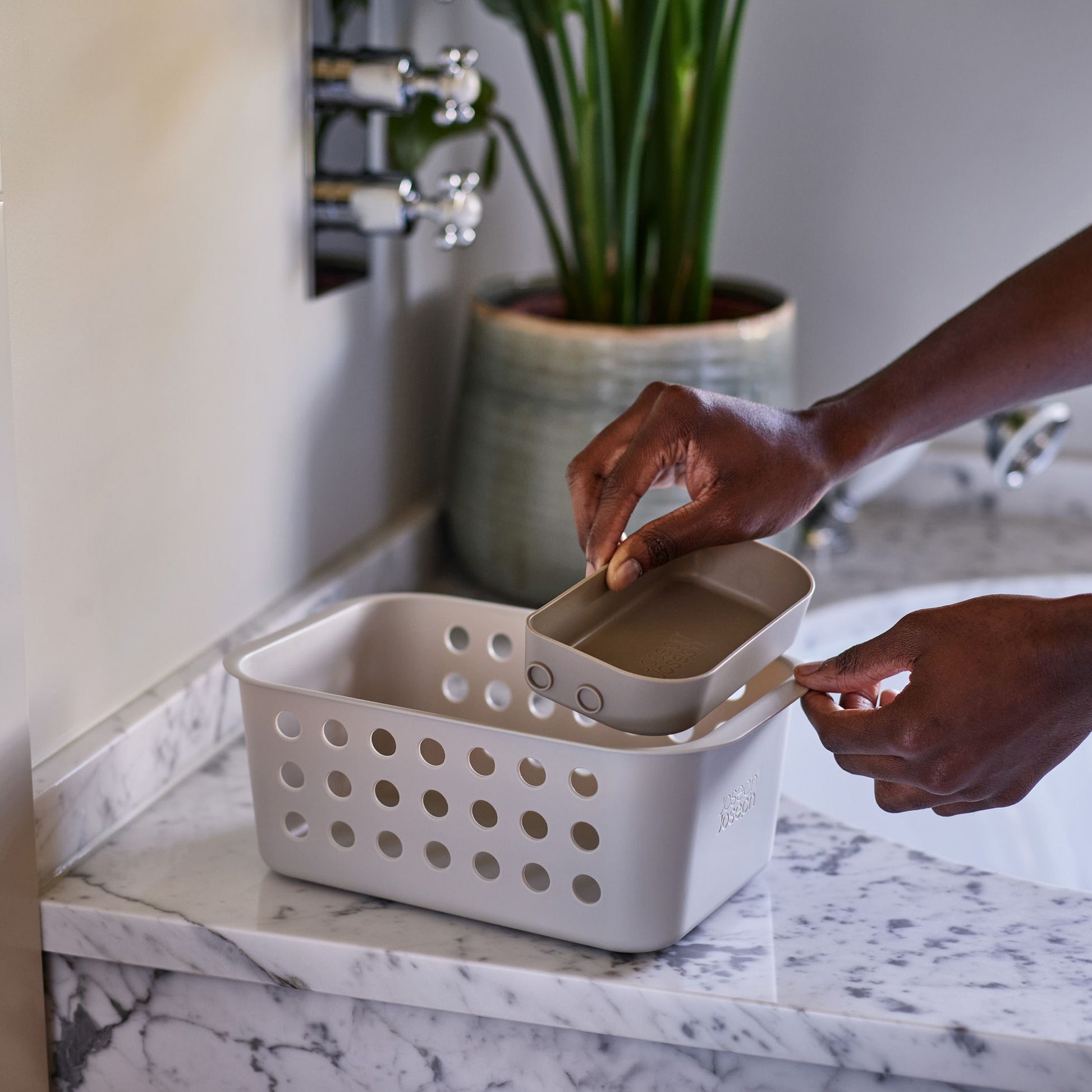 Opbergbox voor badkamer op een marmer wastafel met apart sponsvakje