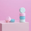 Opgestapelde tabletten allesreiger in roze, blauw en groen op een roze achtergrond