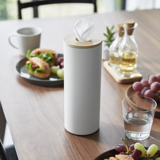 Ronde tissue houder in staal met houten deksel wit op een houten tafel met een gevuld bord en olijfolie