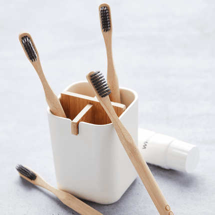 Set van vier houten tandenborstels met houtskoolhaar in houder