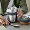 Stainless Steel Food Flask van Black & Blum open vastgehouden door een man op een keukenblad